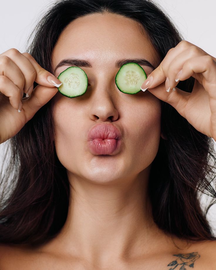 Girl putting cucumber to treat dark circles
